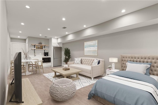 bedroom with light hardwood / wood-style floors and stainless steel refrigerator