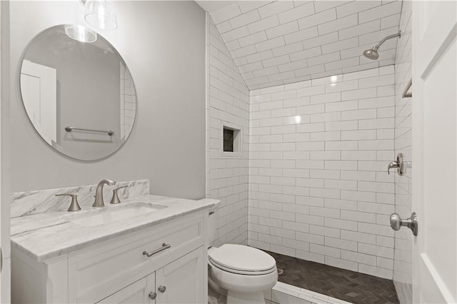 bathroom with a tile shower, vanity, and toilet