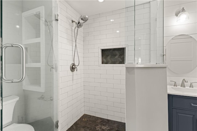 bathroom featuring vanity, a shower with shower door, and toilet