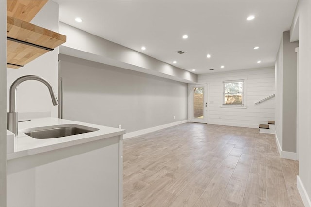 interior space featuring light hardwood / wood-style floors, wooden walls, and sink