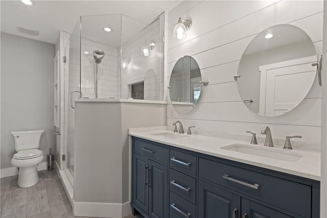 bathroom featuring wood-type flooring, vanity, toilet, and a shower with door