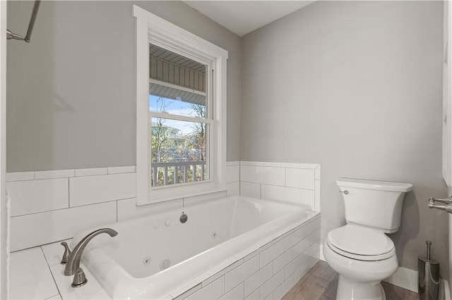 bathroom with tiled tub, wood-type flooring, and toilet