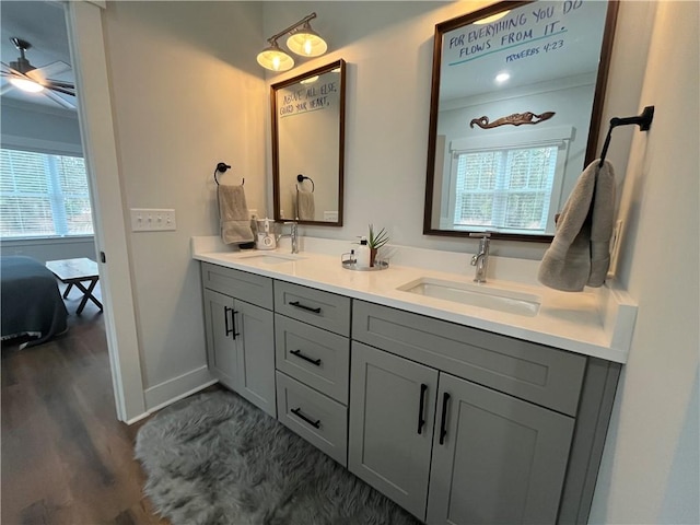 full bath featuring double vanity, baseboards, a sink, and wood finished floors