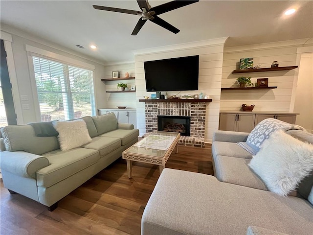 living area with visible vents, ceiling fan, dark wood-type flooring, a brick fireplace, and recessed lighting