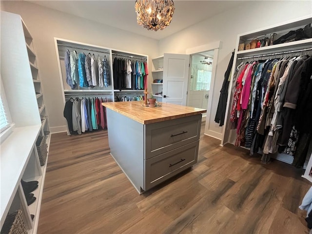 spacious closet featuring dark wood finished floors and a notable chandelier