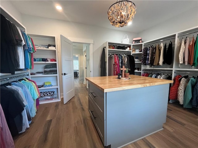 spacious closet with a notable chandelier and dark wood-style flooring