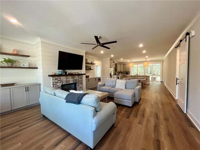 living room with dark wood finished floors, crown molding, and a barn door