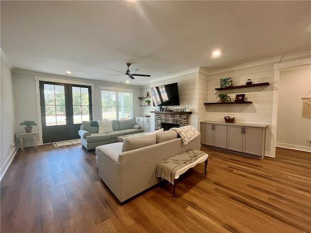 living room with dark wood-style flooring, a fireplace, a ceiling fan, baseboards, and french doors