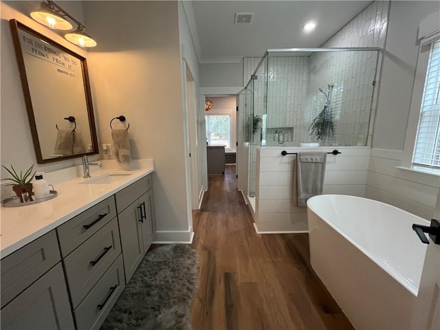 full bath featuring visible vents, a shower stall, vanity, wood finished floors, and a freestanding tub