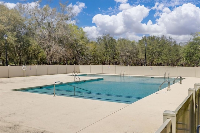 community pool with a patio area and fence