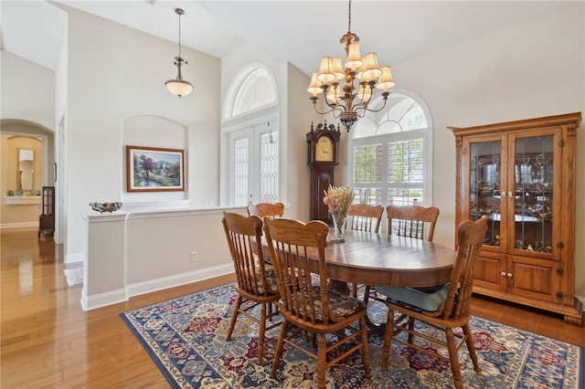 2491 Isles Of St Marys Way, Saint Marys, GA 31558 - dining room featuring arched walkways, light wood-style flooring, a high ceiling, and a chandelier