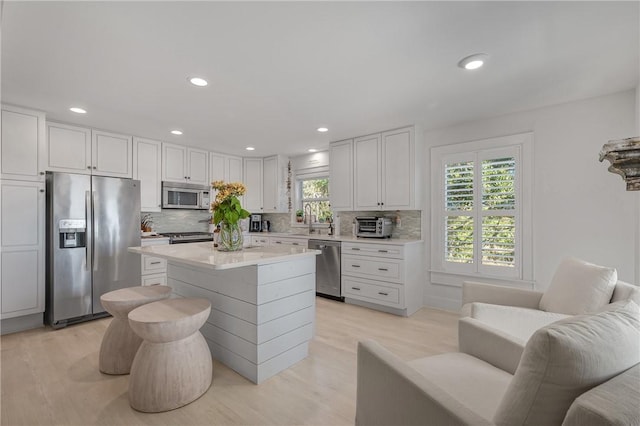 kitchen featuring tasteful backsplash, light countertops, appliances with stainless steel finishes, white cabinets, and a sink