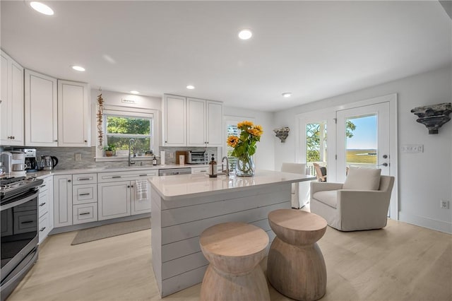 kitchen with white cabinets, a sink, stainless steel appliances, light countertops, and backsplash