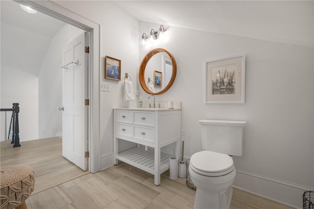 bathroom with vaulted ceiling, vanity, and toilet