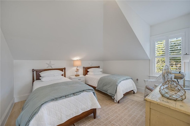 bedroom featuring light wood-style floors, baseboards, and vaulted ceiling