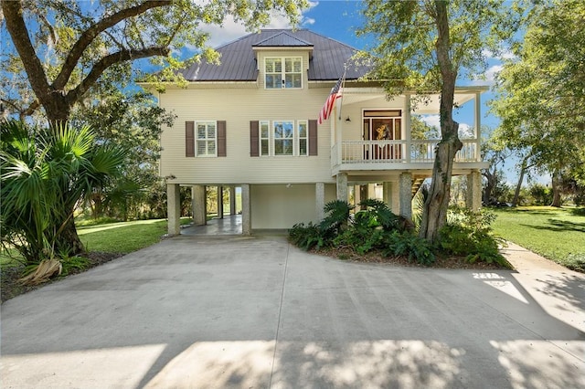 beach home featuring a carport, metal roof, a front lawn, and concrete driveway