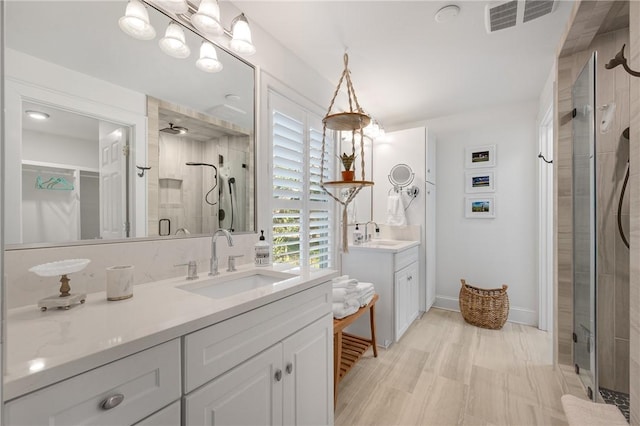 bathroom featuring a stall shower, two vanities, a sink, and visible vents