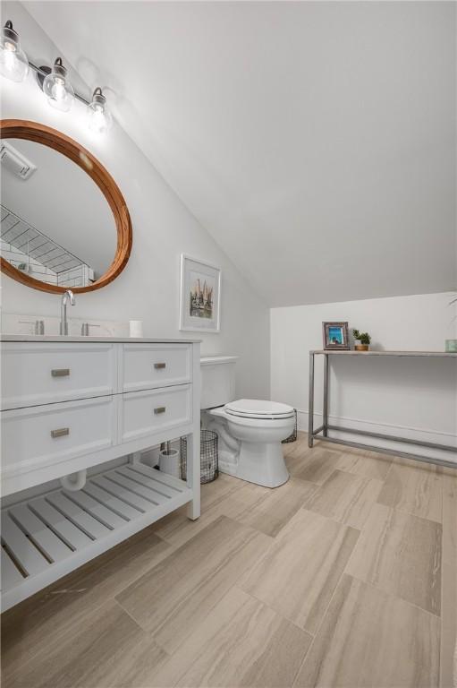 bathroom featuring toilet, vaulted ceiling, and vanity