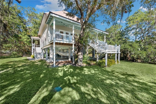 back of house featuring covered porch, stairway, and a lawn