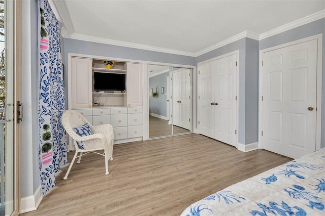 bedroom featuring light hardwood / wood-style flooring, multiple closets, and crown molding