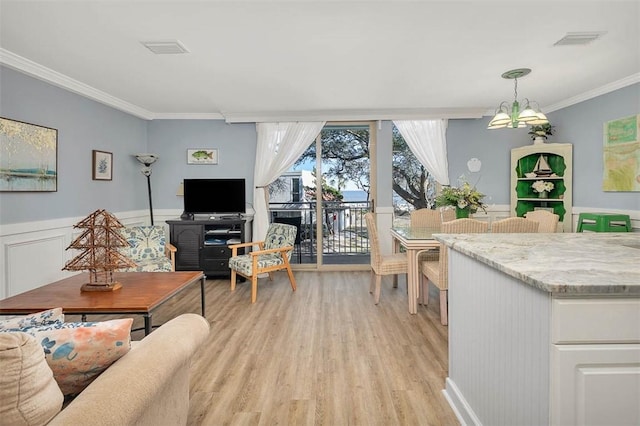 living room featuring crown molding, a notable chandelier, and light wood-type flooring