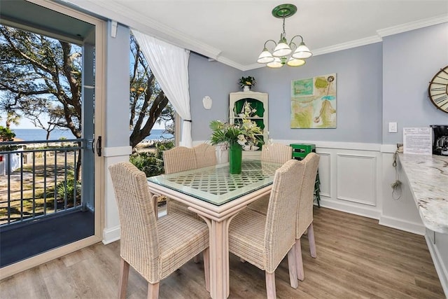 dining area featuring wood-type flooring, a notable chandelier, and ornamental molding