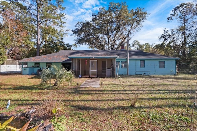 view of front of home featuring a sunroom, a chimney, fence, and a front lawn