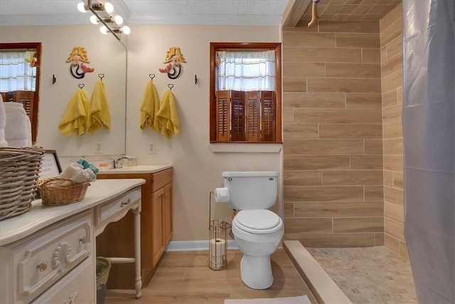 full bathroom featuring a stall shower, toilet, ornamental molding, wood finished floors, and vanity