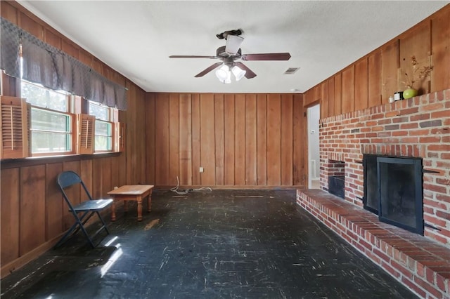 unfurnished living room featuring a ceiling fan, visible vents, a fireplace, and wooden walls