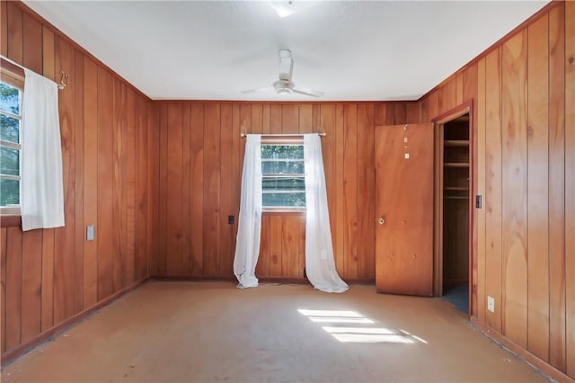 unfurnished room featuring wood walls and ceiling fan