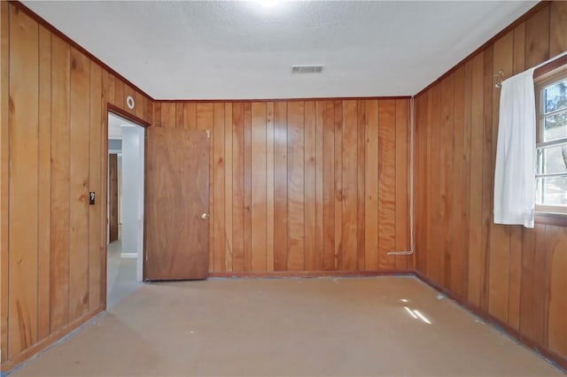 unfurnished room with wood walls and visible vents