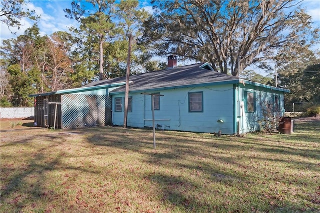 back of property with a chimney, fence, and a yard