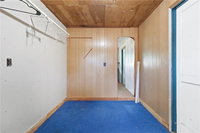 spacious closet with arched walkways and dark colored carpet