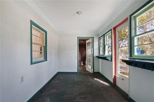 empty room featuring unfinished concrete floors, baseboards, and crown molding