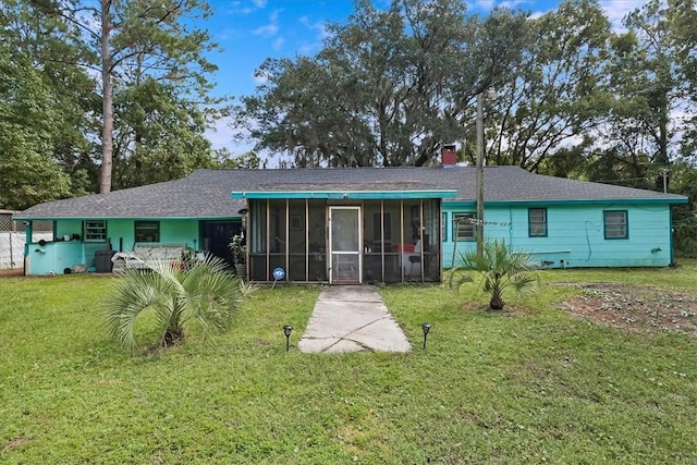 back of property with a lawn, a chimney, and a sunroom