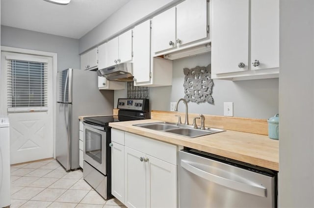 kitchen featuring appliances with stainless steel finishes, light tile patterned floors, white cabinetry, and sink