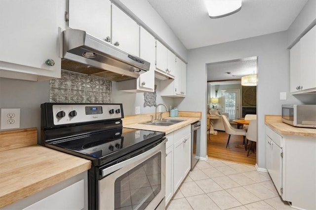 kitchen featuring sink, white cabinets, stainless steel appliances, and light tile patterned floors