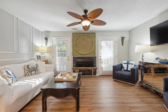 living room with wood-type flooring, a textured ceiling, plenty of natural light, and ceiling fan