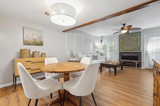 dining area featuring a healthy amount of sunlight, ceiling fan, beamed ceiling, and light hardwood / wood-style floors