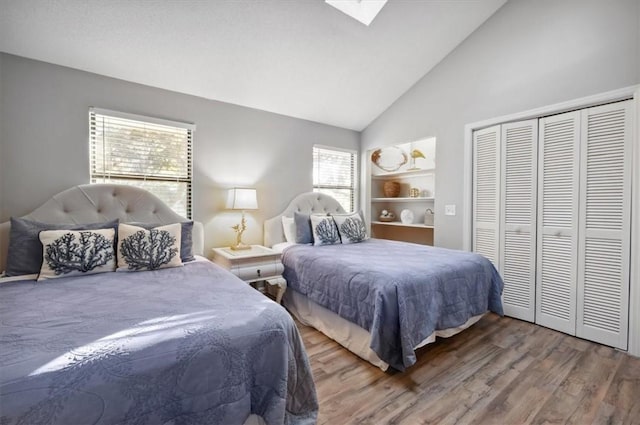 bedroom with wood-type flooring, high vaulted ceiling, and a closet