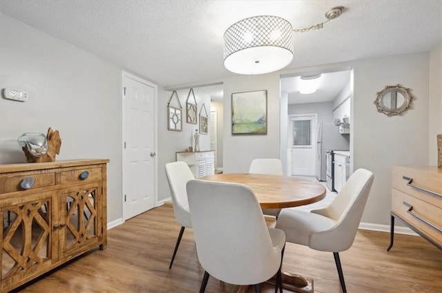 dining area with a textured ceiling and light wood-type flooring