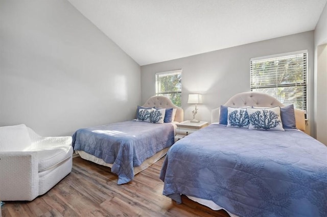 bedroom with multiple windows, wood-type flooring, and vaulted ceiling