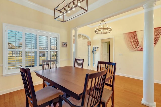 dining area with an inviting chandelier, hardwood / wood-style flooring, ornamental molding, and decorative columns