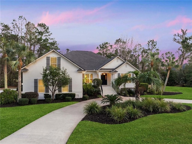 view of front of house with driveway, a front yard, and stucco siding