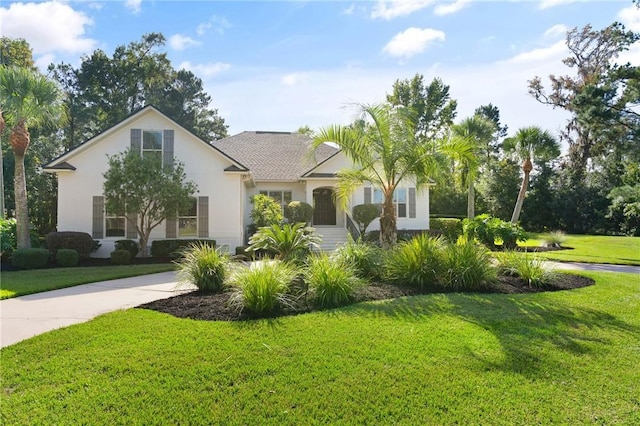 view of front facade with a front yard, driveway, and stucco siding