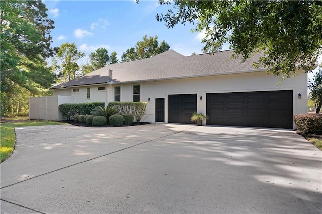 ranch-style home featuring a garage, driveway, and stucco siding