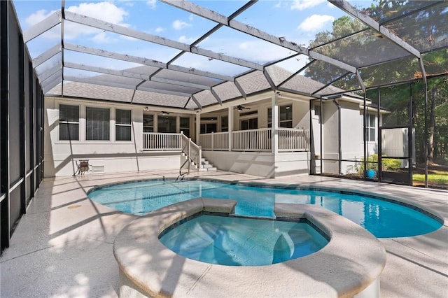 view of swimming pool with glass enclosure, ceiling fan, a patio area, and a pool with connected hot tub