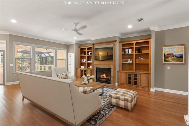 living area with a warm lit fireplace, baseboards, crown molding, and light wood finished floors