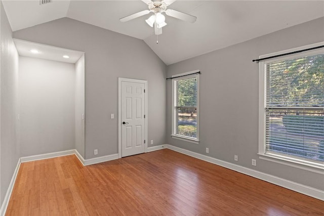 spare room with light wood-style floors, lofted ceiling, ceiling fan, and baseboards