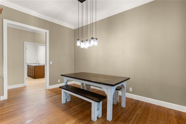 dining room featuring light wood-style floors, ornamental molding, and baseboards